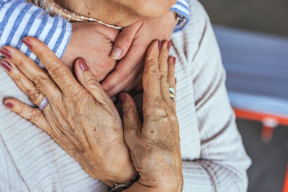 Close-up of an older woman's hands resting over another person's hand